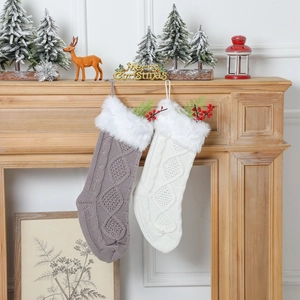 Détail de chaussettes de Noël en tricot gris et blanc suspendues à une cheminée en bois
