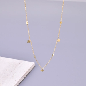 Close-up of a 18K gold-plated star pendant necklace on a marble stone display