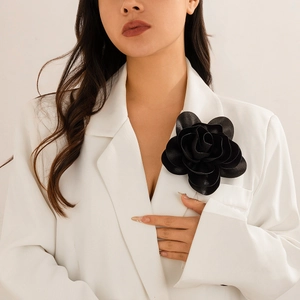 Close-up of a stylish black rose flower brooch styled on a white blazer lapel