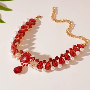 Detail of vintage necklace with red teardrop gems, pearls and golden floral accents