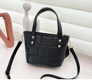 Close-up of black quilted bucket bag with gold studs and mini coin purse accessory