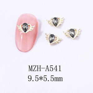 Macro detail of winged heart nail charms with gray teardrop rhinestones on pink nails