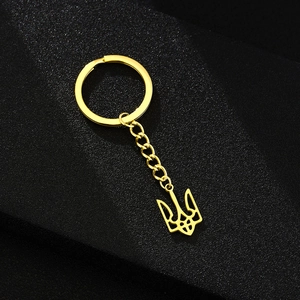 Golden trident coat of arms keychain in polished steel on a black textured background