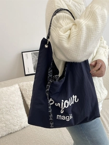 Dark blue canvas tote bag with leopard print strap shown on shoulder in home setting