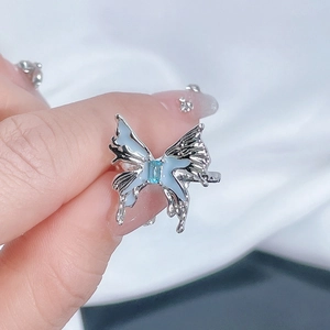 Macro shot of silver butterfly ring featuring light blue enamel wings and rectangle gemstone