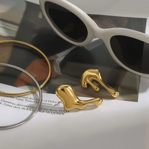 Macro shot of gold lava stud earrings and metallic bracelets on a lifestyle magazine