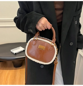 Detail showing brown leather pillow bag with cream faux fur trim and gold metal logo plaque