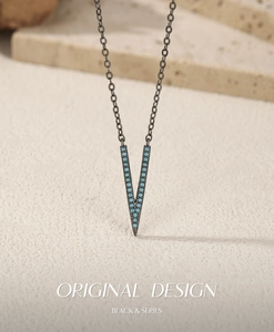 Macro shot of V-shaped black metal necklace featuring turquoise bead setting on stone base