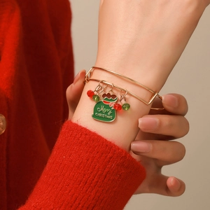 Close-up of golden Christmas charm bracelet with Merry Christmas bag on wrist