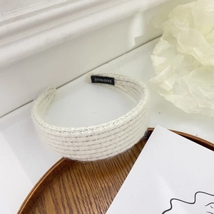 Detail shot of white knitted headband featuring a black woven HAND MADE label inside
