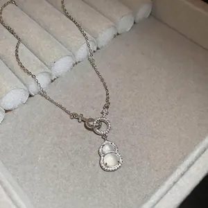 Elegant silver gourd pendant necklace with white zircon stones on a jewelry display box