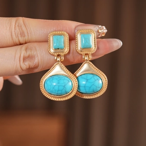Detail of vintage teardrop earrings in matte gold finish with turquoise resin stone