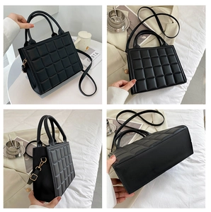 Detail view of black quilted faux leather handbag with golden hardware and square pattern