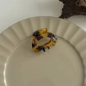 Detailed view of leopard tortoise shell claw clip on a beige ripple ceramic tray