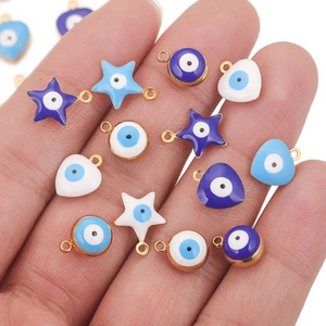 Evil eye enamel charms in round star and heart shapes held in hand for jewelry making