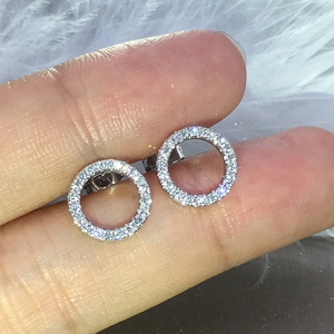 Macro shot of silver circular stud earrings with white zircon pavé on a feather background