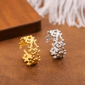 Golden and silver laurel leaf adjustable rings on a premium display with feathers