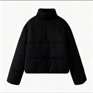 Detail of black cable knit high neck puffer jacket with ribbed cuffs and quilted texture