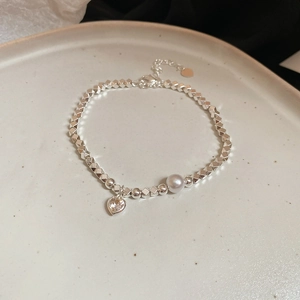 Dettaglio ravvicinato del bracciale con ciondolo a cuore in zircone e perle su vassoio bianco