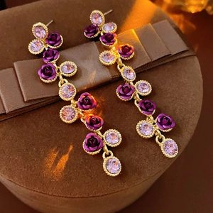 Détail macro de boucles d'oreilles rose avec cristaux et chaînes sur un coffret cadeau