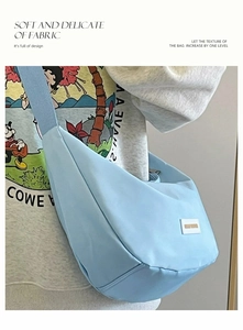 Dettaglio della borsa a mezzaluna in nylon azzurro con tracolla larga e placchetta logo