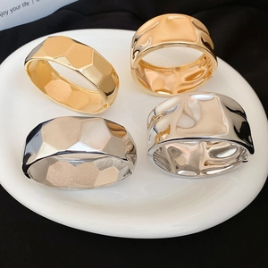 Detailed macro view of wide metallic cuff bracelets with hammered and geometric textures