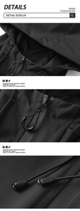 Detail view of the drawstring hood, central zipper, and adjustable hem on this black outdoor jacket