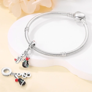Detail of silver music charms featuring a black guitar with red rose and treble clef