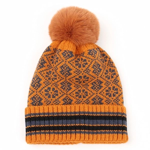 Detail of orange knitted beanie with faux fur pom and grey geometric snowflake pattern