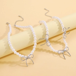 Detailed view of silver bow-knot pearls necklaces with lobster clasps on cylindrical stand
