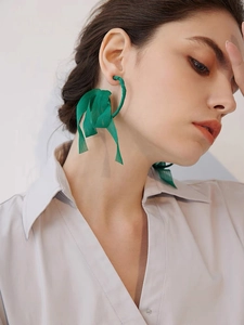 Detailed view of large green silk wrapped hoop earrings worn by a fashion model