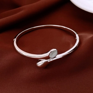 Macro shot of silver metal bangle with cat eye stone on red satin fabric background