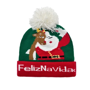 Détail du motif Feliz Navidad tricoté avec Père Noël et renne sur un bonnet de Noël