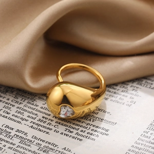 Close-up of a gold-plated teardrop ring with heart-shaped zircon on vintage book pages