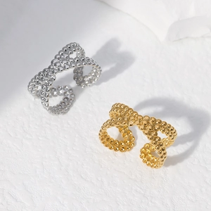 Detailed view of criss-cross dot-textured rings in polished gold and silver finishes