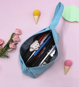 Dettaglio interno di un astuccio blu in tessuto con penne e accessorio a forma di orso