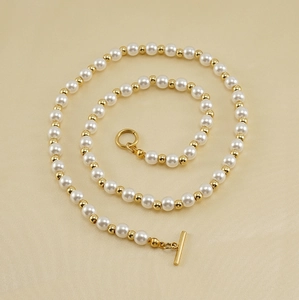Vue détaillée du collier de perles avec perles dorées et fermoir OT sur tissu beige