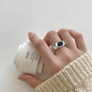 Irregular 925 silver ring with hammer texture and oval blue stone worn with knitwear