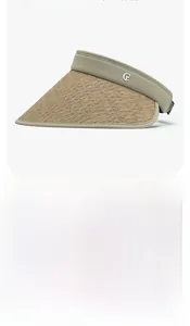 Detail of beige wide-brim straw visor showing UV protection fabric and metal logo