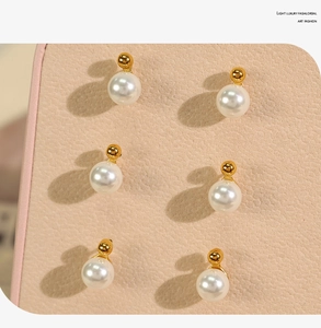Macro view of elegant white pearls with golden metal bases on pink leather texture