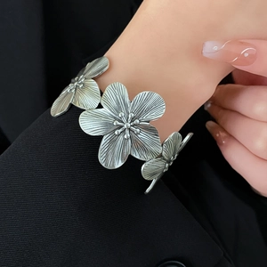 Detail of vintage silver flower cuff featuring textured metal petals on model
