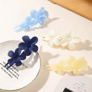 Detailed view of matte flower hair clips in blue, white and yellow resin finish