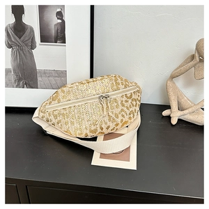 Detail of straw woven waist bag with golden metallic print and adjustable strap
