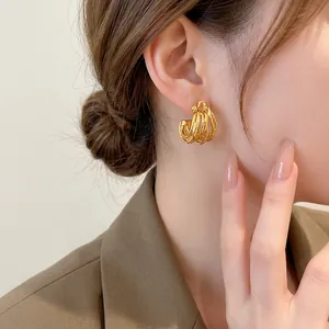 Irregular geometric C-shaped gold-plated wrap hoop earrings shown on a female model