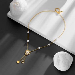 Close-up of gold titanium necklace with pearls and camellia shell flower pendant