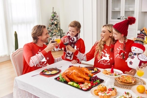 Famiglia con pigiami natalizi rossi con renne durante una cena festiva di Natale in casa