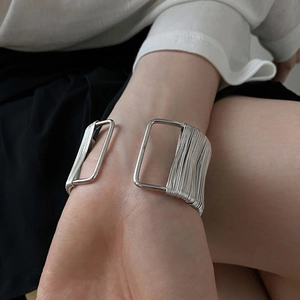 Close-up of a silver multi-layer wire wrapped geometric open cuff bracelet on wrist