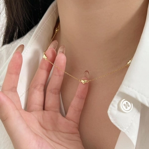 Detail of a gold heart pendant necklace worn by a model against a white shirt