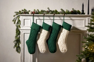 Close-up of knitted Christmas stockings with cable patterns hanging on a fireplace mantel