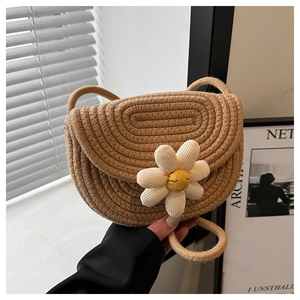 Close-up of khaki woven saddle bag featuring a cute white daisy flower with smiling face